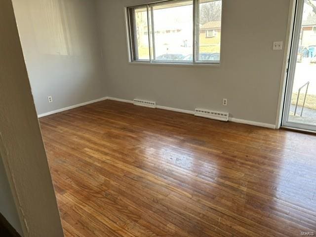 unfurnished room with dark hardwood / wood-style floors and baseboard heating