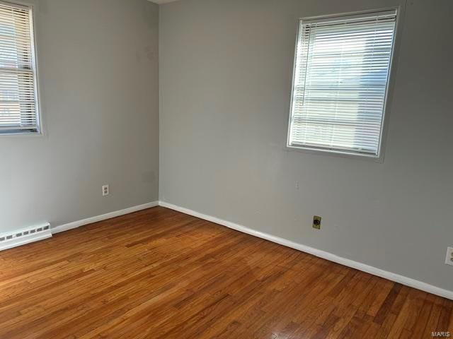 empty room featuring a baseboard heating unit and hardwood / wood-style floors