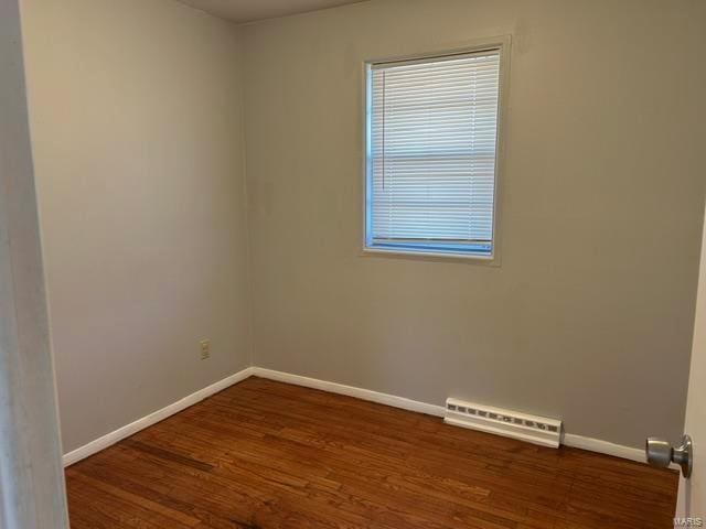 spare room with a baseboard heating unit and dark wood-type flooring