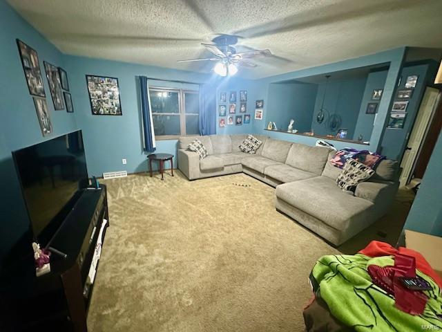 living room featuring ceiling fan, a textured ceiling, and carpet flooring