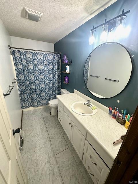 bathroom with vanity, toilet, and a textured ceiling