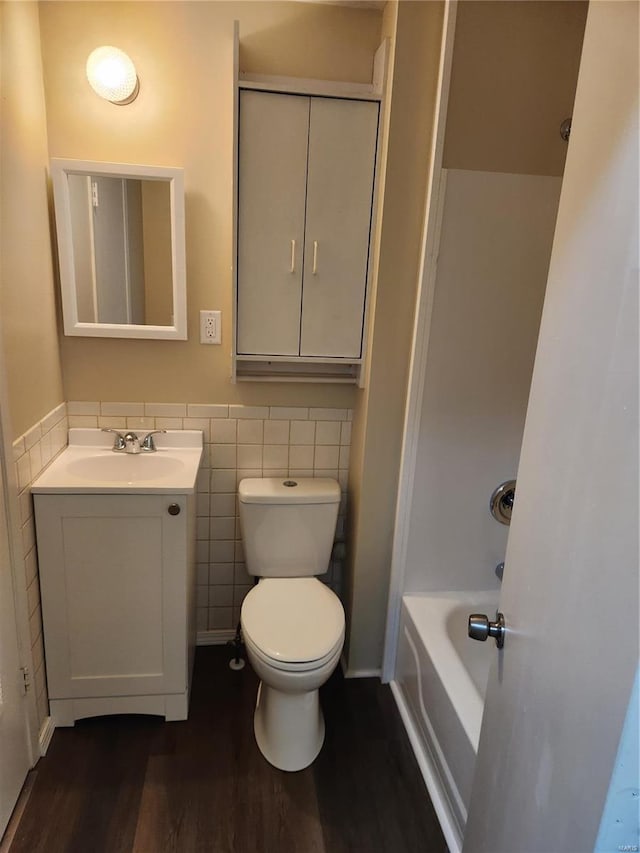 bathroom featuring vanity, wood-type flooring, tile walls, and toilet