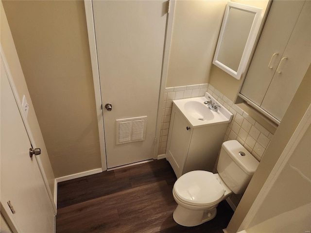 bathroom with wood-type flooring, tile walls, vanity, and toilet