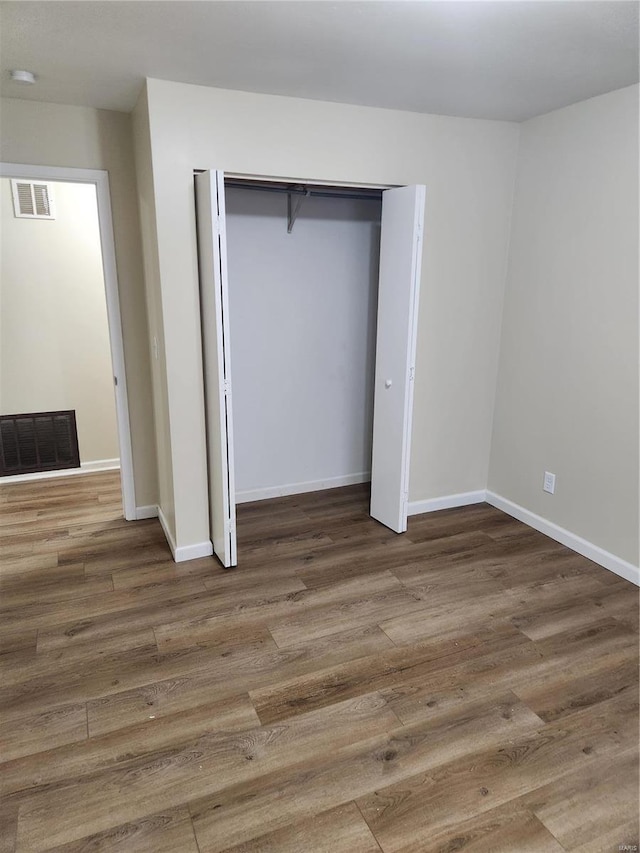 unfurnished bedroom with dark hardwood / wood-style flooring and a closet