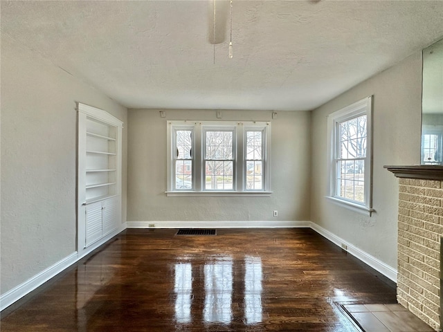 interior space with a textured ceiling, baseboards, visible vents, and built in features