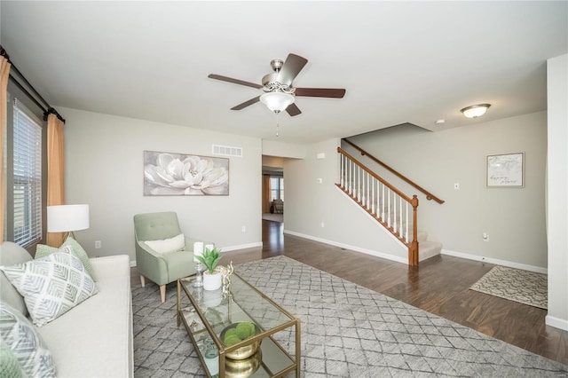 living area with stairway, wood finished floors, visible vents, and baseboards