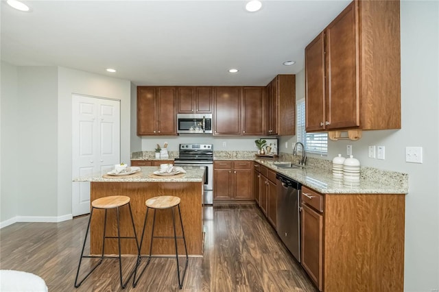 kitchen featuring dark wood-style floors, a breakfast bar, stainless steel appliances, a kitchen island, and a sink