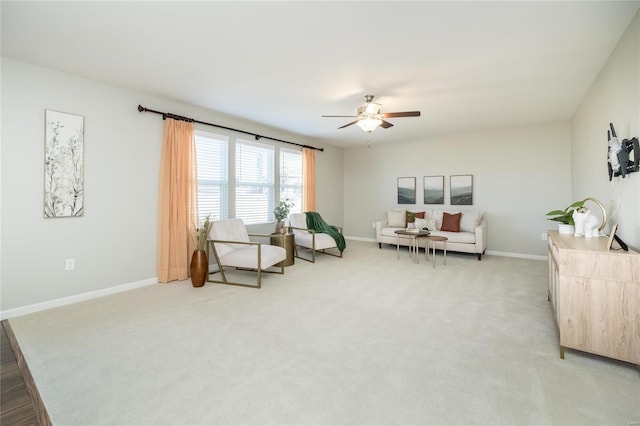 living area featuring baseboards, ceiling fan, and light colored carpet