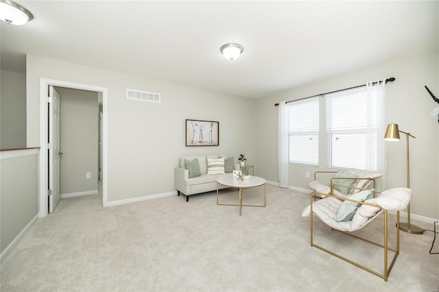 living area featuring light colored carpet, visible vents, and baseboards