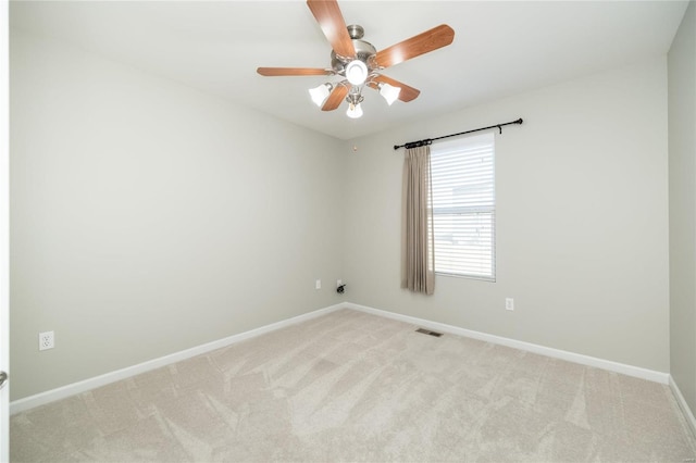 spare room with light carpet, ceiling fan, visible vents, and baseboards