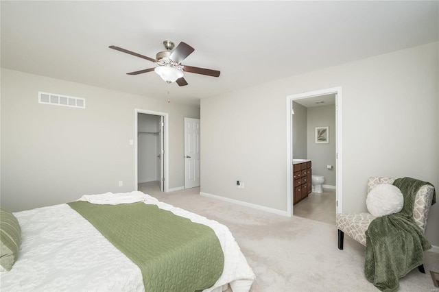 bedroom featuring ceiling fan, ensuite bathroom, light colored carpet, visible vents, and baseboards