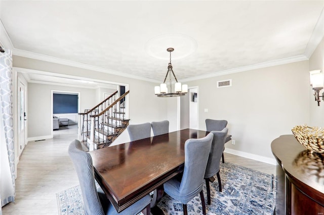 dining area featuring crown molding, a chandelier, and light wood-type flooring