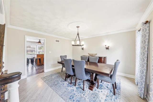 dining area with crown molding, a chandelier, and light wood-type flooring