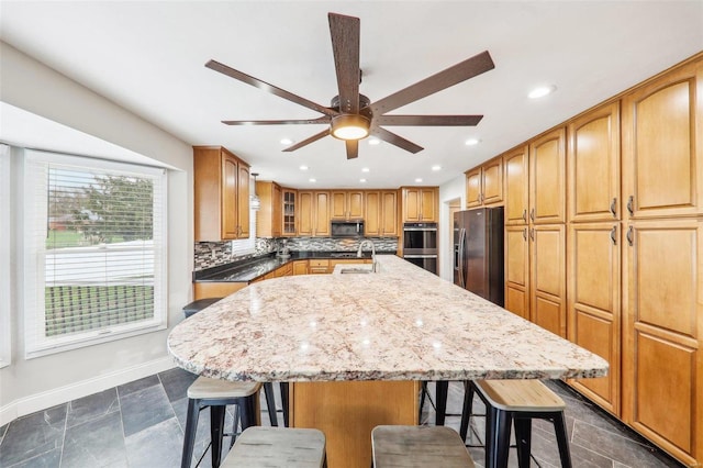 kitchen with sink, stainless steel appliances, a kitchen bar, and an island with sink