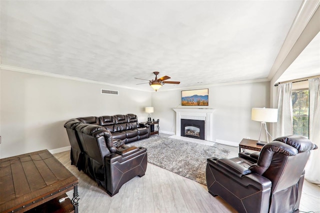 living room featuring crown molding, ceiling fan, and light wood-type flooring