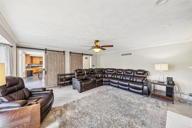 living room with crown molding, a barn door, and ceiling fan