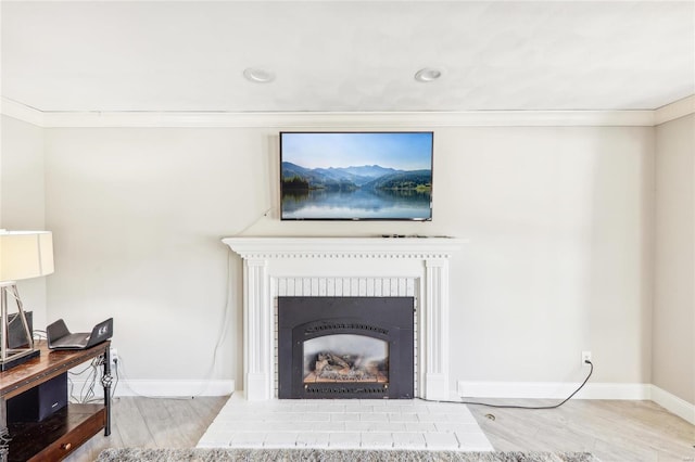 living room with ornamental molding, a brick fireplace, and light hardwood / wood-style flooring