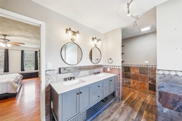 bathroom with hardwood / wood-style flooring, ceiling fan, vanity, and tile walls