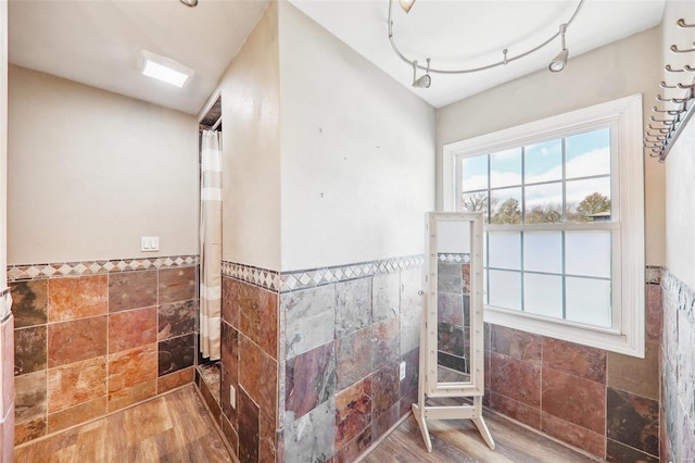 bathroom with hardwood / wood-style flooring, tile walls, and walk in shower