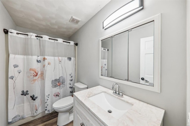 bathroom with vanity, hardwood / wood-style flooring, toilet, and walk in shower