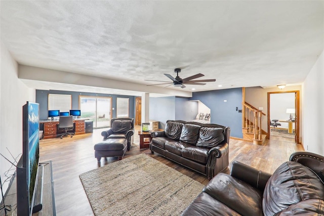 living room featuring ceiling fan, a textured ceiling, and light wood-type flooring