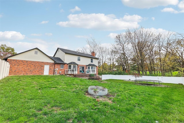 rear view of house featuring a trampoline and a lawn