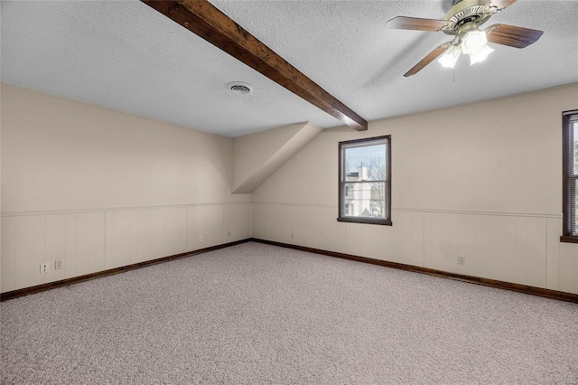 bonus room with beamed ceiling, ceiling fan, carpet, and a textured ceiling