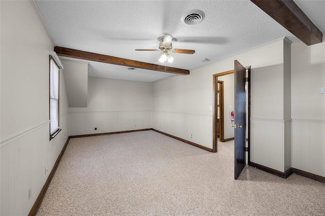 empty room with ceiling fan, beam ceiling, and a textured ceiling