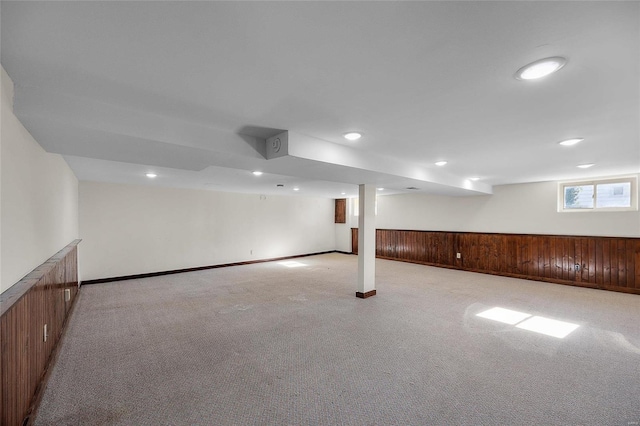 basement featuring light colored carpet and wood walls