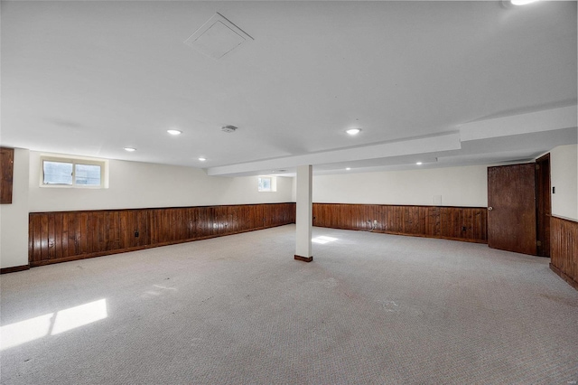 basement with light carpet and wooden walls