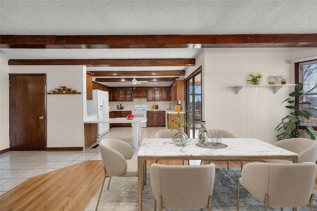 dining room with ceiling fan, beamed ceiling, a textured ceiling, and light tile patterned flooring