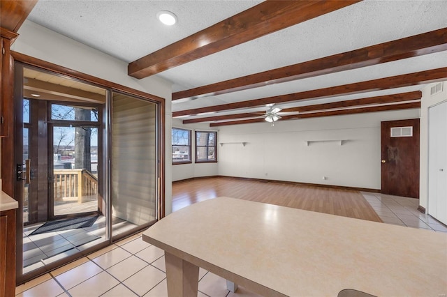 interior space featuring ceiling fan, beam ceiling, a textured ceiling, and light tile patterned floors