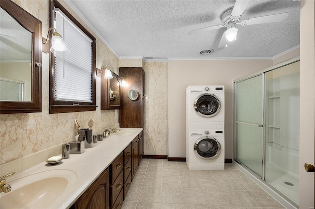 bathroom featuring ornamental molding, stacked washer / drying machine, and a textured ceiling