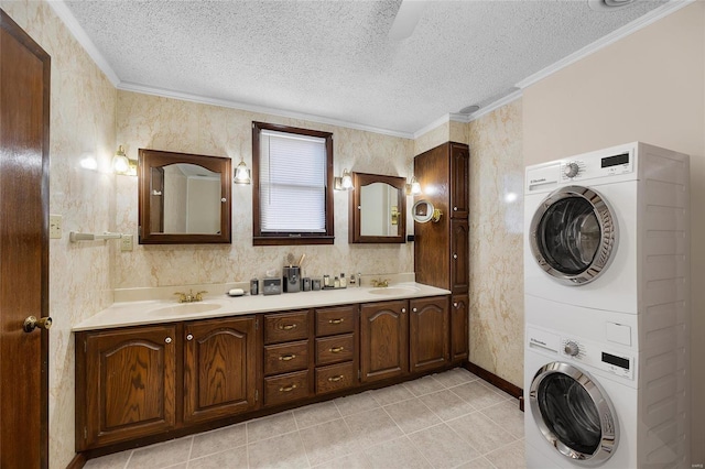 bathroom featuring vanity, ornamental molding, a textured ceiling, and stacked washing maching and dryer