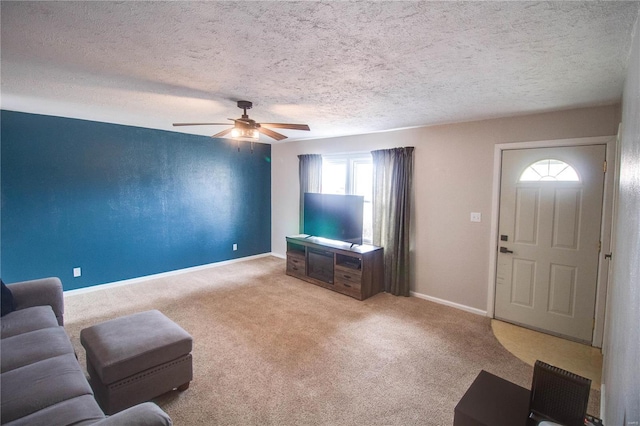 living room with ceiling fan, baseboards, a textured ceiling, and light colored carpet