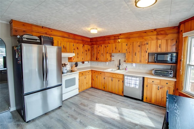 kitchen with stainless steel appliances, light countertops, light wood-style floors, a sink, and under cabinet range hood