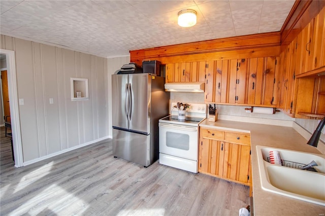 kitchen featuring electric range, freestanding refrigerator, light countertops, under cabinet range hood, and a sink