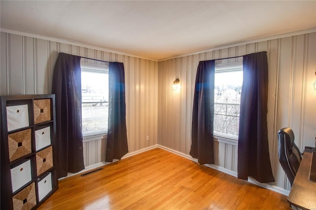 unfurnished room featuring a wealth of natural light, visible vents, light wood-style flooring, and baseboards