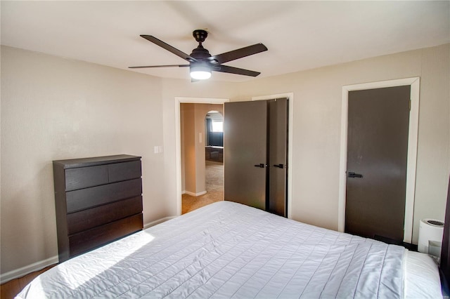 bedroom with baseboards, arched walkways, ceiling fan, and a closet