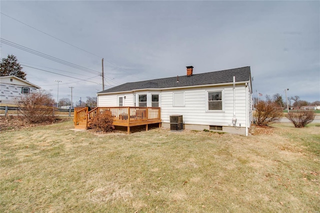 rear view of house featuring a yard, roof with shingles, a chimney, and a wooden deck