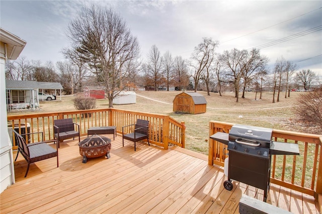 wooden terrace with a fire pit, a storage unit, grilling area, and an outdoor structure