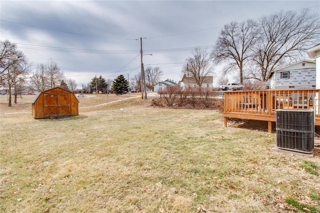 view of yard featuring an outbuilding, central AC, a wooden deck, and a shed