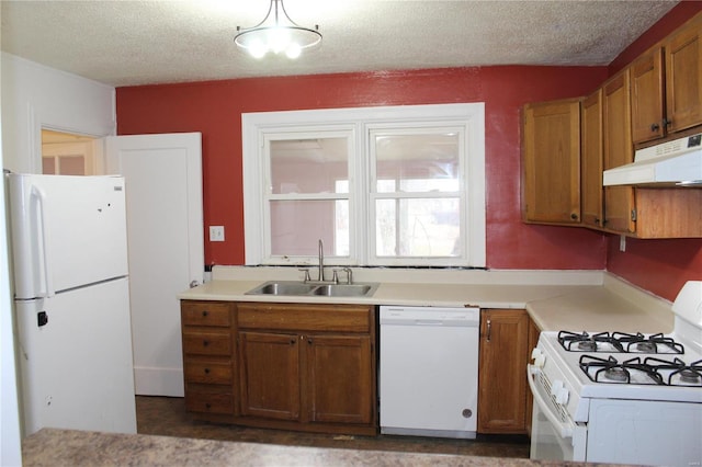 kitchen with sink, white appliances, hanging light fixtures, and a textured ceiling