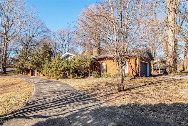 view of property exterior with an attached garage and a chimney