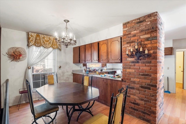 kitchen with brown cabinets, decorative light fixtures, light countertops, light wood-style floors, and a chandelier