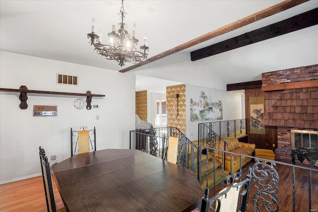 dining space with vaulted ceiling with beams, wood finished floors, visible vents, baseboards, and an inviting chandelier