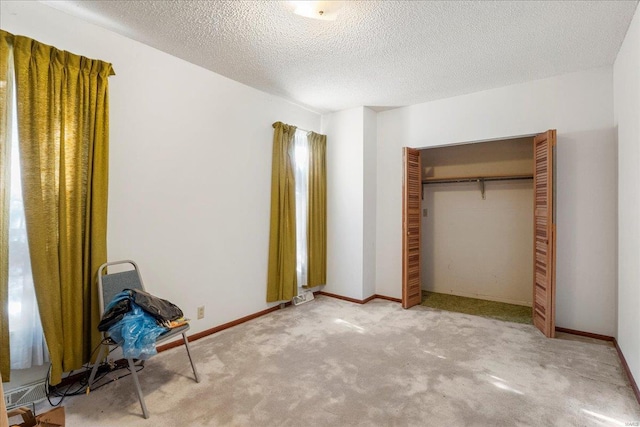 unfurnished bedroom with carpet floors, a closet, a textured ceiling, and baseboards