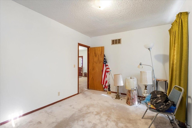 carpeted empty room with baseboards, visible vents, and a textured ceiling