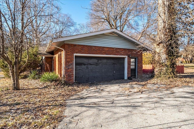 view of property exterior featuring a garage, brick siding, and aphalt driveway