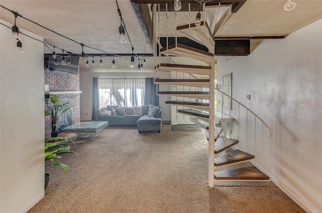 basement with a brick fireplace, rail lighting, and carpet